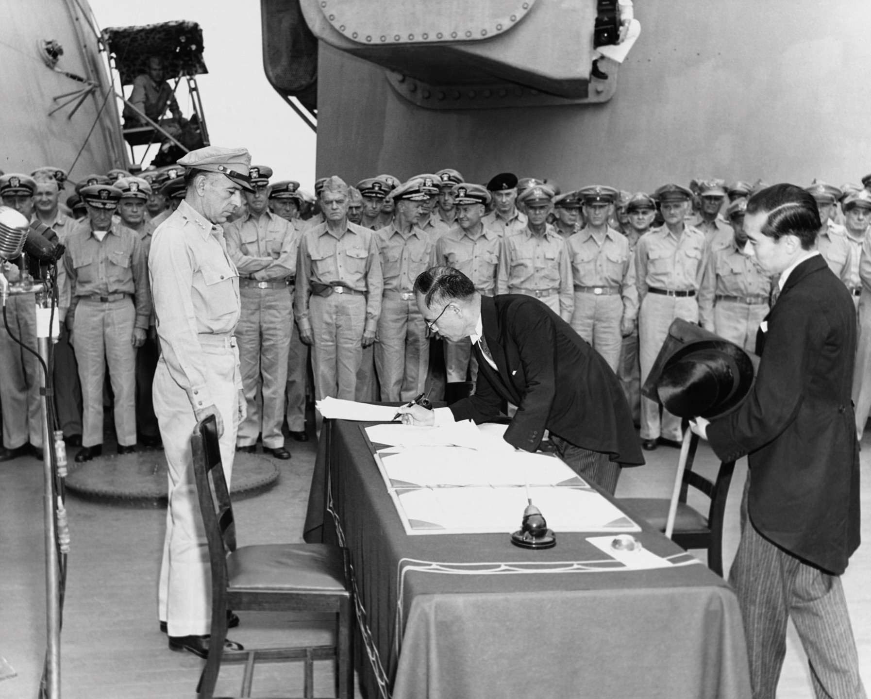 Japanese foreign affairs minister Mamoru Shigemitsu signs the Japanese Instrument of Surrender aboard the USS Missouri as American General Richard K. Sutherland watches.